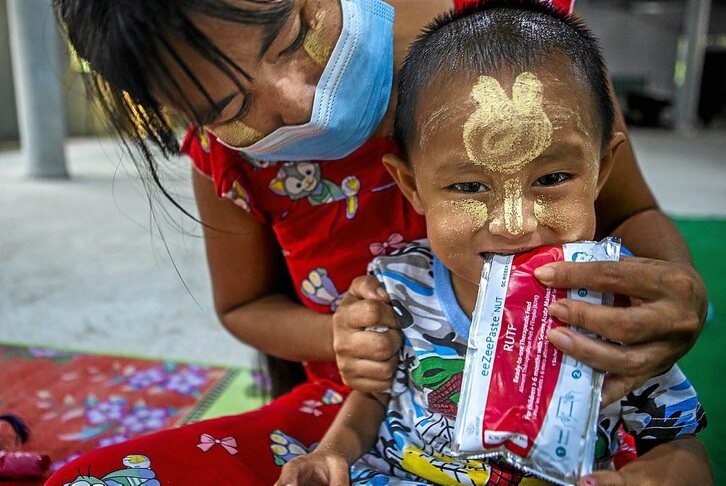 Min Hein Htet izeneko 3 urteko mutikoari erabiltzeko prest dagoen elikagai terapeutikoa ematen ari zaio bere ama.