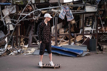 Un joven pasa con su skate ante una tienda destruida por la explosión de un misil en Kramatorsk.