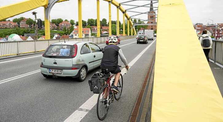 Un coche pasa junto a un ciclista en Soenderborg, Dinamarca.