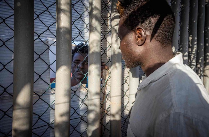 Dos hombres hablan a sendos lados de la valla del Centro de Estancia Temporal de Inmigrantes de Melilla. 