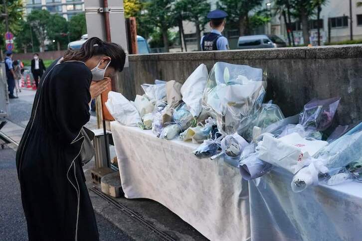 Una mujer ora junto a la ofrenda floral en memoria de Abe, frente a la sede del PLD en Tokio.