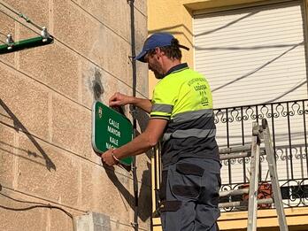 Un empleado municipal comienza a colocar las placas bilingües.