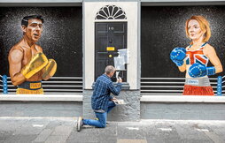 El artista Ciaran Gallagher termina en Belfast un mural que presenta como boxeadores a Rishi Sunak (i) y Liz Truss (d).