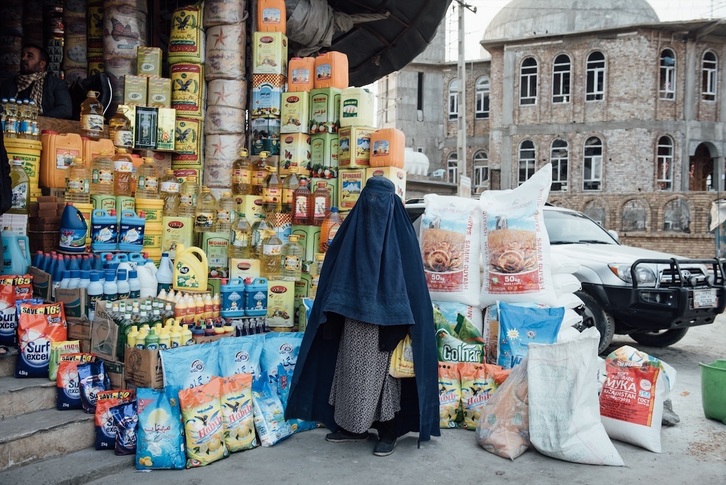 Una mujer con burka ante una tienda en Kabul.