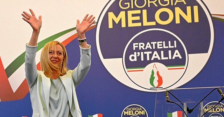 Giorgia Meloni, hauteskundeetan lortutako garaipena ospatzen, alderdiaren logoa atzean duela. (Andreas SOLARO / AFP PHOTO)