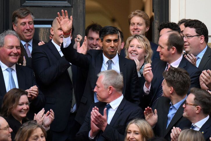 El desde hoy nuevo primer ministro británico, Rishi Sunak, saluda a su llegada a la sede del Partido Conservador.