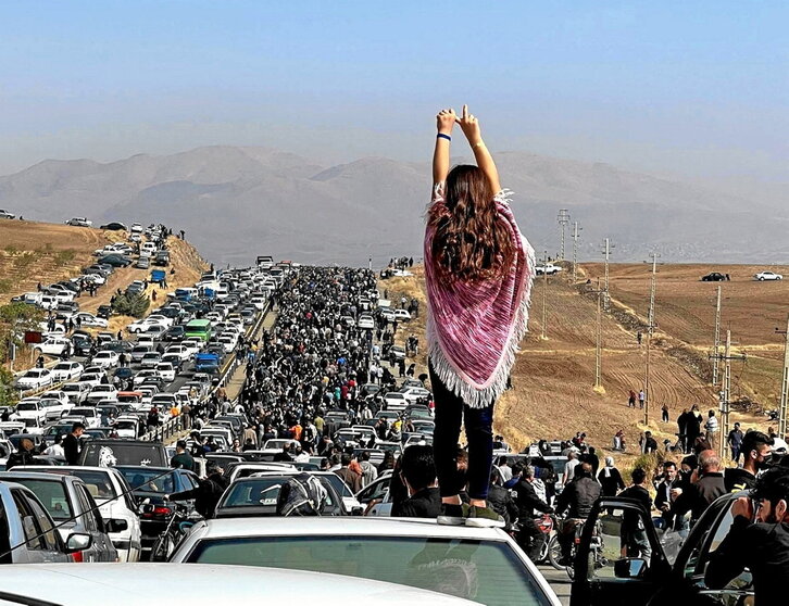 Una mujer, sobre un vehículo en medio de la multitudinaria marcha hacia el cementerio de Aichi.