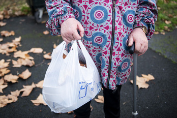 Una mujer de edad porta una bolsa con comida donada por una asociación solidaria en Baiona.