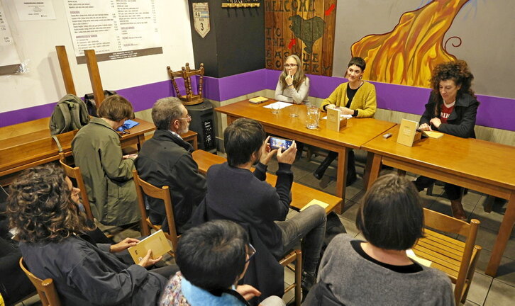 Mahaian, ezker-eskuin, Josebe Blanco, Leire Milikua eta Jule Goikoetxea, «Lur gainean, itzal azpian» obra aurkezten.