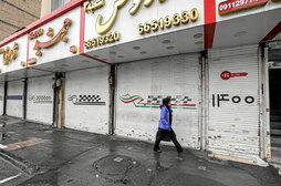 Una mujer pasa ante varios comercios cerrados ayer en Teherán.