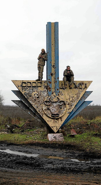 Soldadu ukrainarrak Kharkov eta Donetsk eskualdeak banatzen dituen muga iragartzen duen monumentuaren gainean.