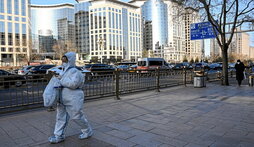 Una mujer camina por Pekín con un equipo de protección.