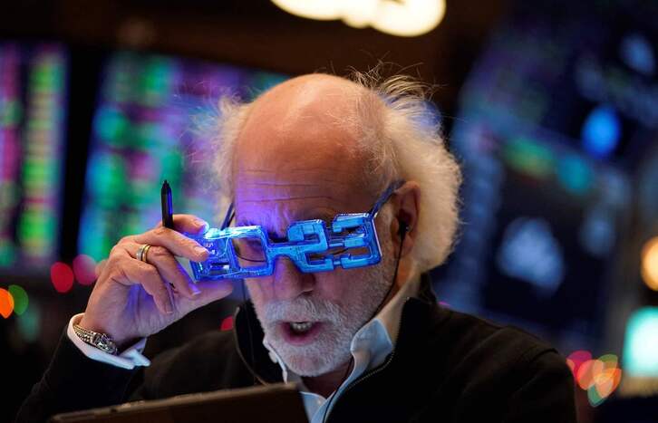 Un corredor con unas gafas alusivas al nuevo año observa su pantalla en la Bolsa de Nueva York. 