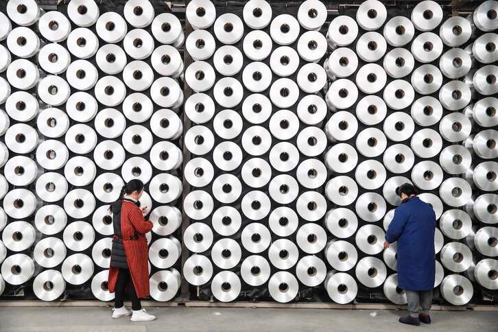 Trabajadores examinando la producción en una fábrica textil china