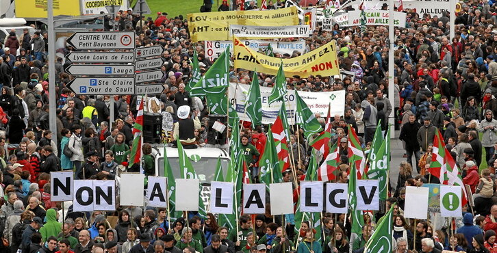 Manifestación multitudinaria que reunió a miles de personas en Baiona contra el proyecto del TAV en 2012. En la siguiente página, concentración para denunciar la construcción de la línea de alta velocidad en 2014 en Angelu.