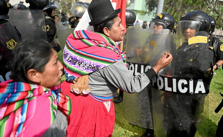 Mujeres indígenas gesticulan frente a un cordón policial en Lima.