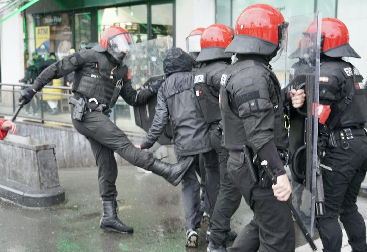 Un ertzaina propina una patada a una persona que protestaba por la presencia de los falangistas en Donostia.