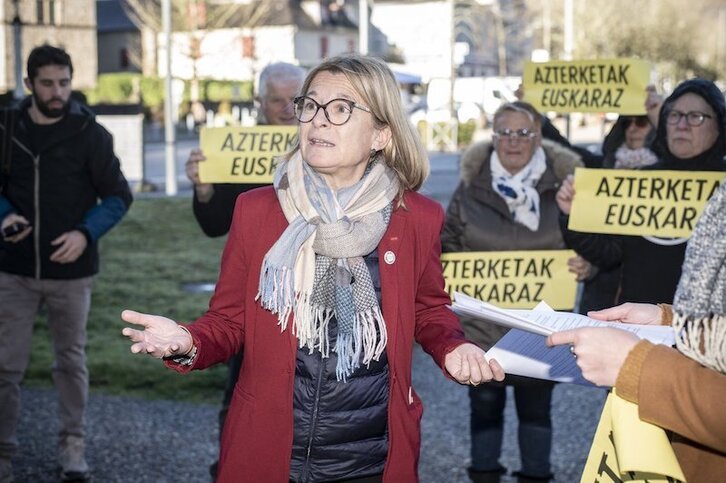 Anne Bisagni-Faure, se explica, rodeada de personas que portan carteles en favor de los exámenes en euskara.