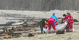 Rescatistas manejan una bolsa para cadáveres en la playa, entre restos del naufragio, cerca de Crotona.