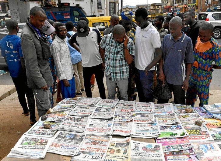 Varios hombres leen las portadas de los diarios en Lagos.