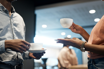 Un empleado y una empleada toman café en una oficina.