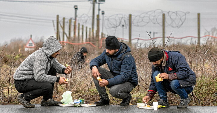 Migrantes comen en un campo de refugiados en Mardyck, al norte del Estado francés.