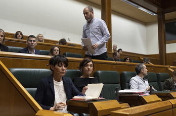 Josu Estarrona se dirige a la tribuna de oradores entre los escaños de EH Bildu.