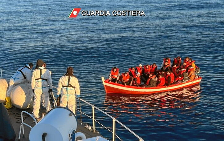 Imagen proporcionada por la Guardia Costera que muestra a un pequeño bote con una veintena de personas migrantes.