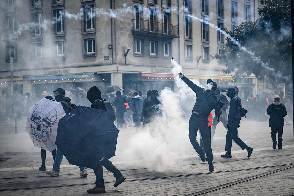 Un manifestante lanza un proyectil de gas lacrimógeno hacia la policía antidisturbios en medio de enfrentamientos durante una manifestación el Primero de Mayo, más de un mes después de que el gobierno impulsara una la reforma de las pensiones.