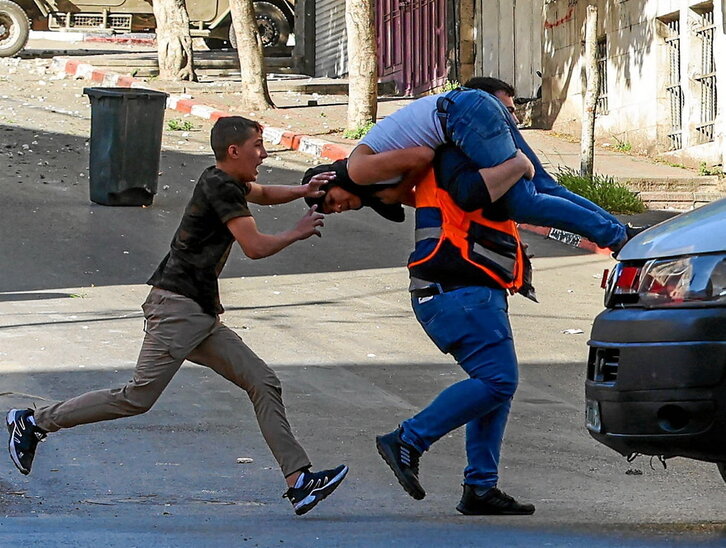 Un hombre lleva a un herido en la protesta tras la redada israelí en Nablús.
