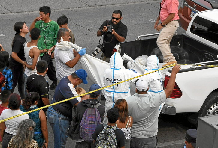 Forentseak, banda batek hildako bi gazteren gorputzak kentzen, Tegucigalpan.
