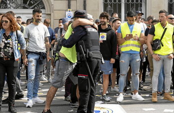 Un ertzaina manifestante y un uniformado se abrazan sobre las vías del tranvía.