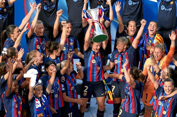 Irene Paredes levanta el trofeo de campeonas rodeada por sus compañeras.