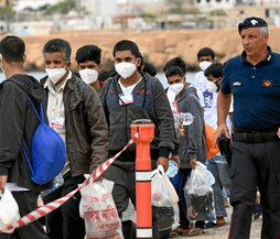 Migrantes esperan en una cola en la isla de Lampedusa.
