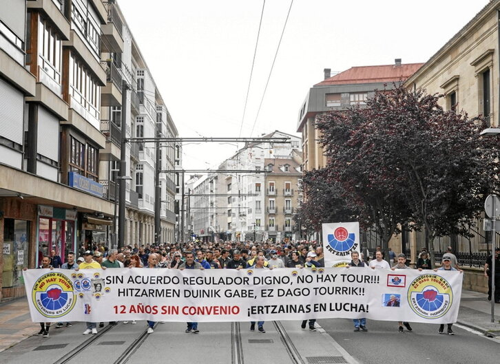 Manifestación de los agentes de la Ertzaintza y detalle de la pancarta con menciones a la directora de recursos humanos del Deparatamento de Seguridad.