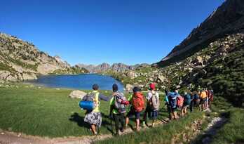 Los marchistas disfrutan de las vistas de un lago de los Pirineos.