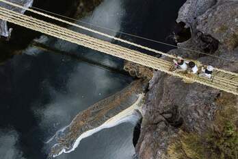 Vista aérea de personas de diferentes comunidades participando en la renovación anual del puente de cuerda Q'eswachaka.