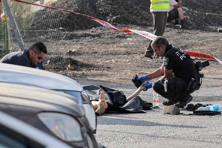 Un policía israelí inspecciona la documentación de una de las víctimas.