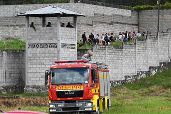 Un camión de bomberos frente a la cárcel, donde los guardias vigilan a varias presas.