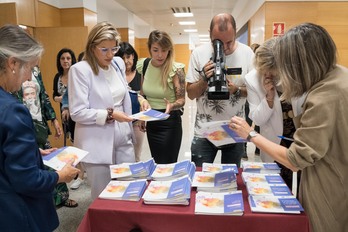 Asistentes a la presentación cogen las recién estrenadas guías. 