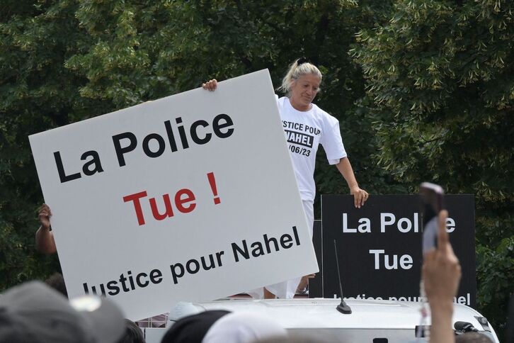 La madre del joven Nahel porta un cartel con el lema «¡La Policía mata»!.