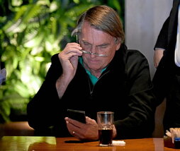Jair Bolsonaro mira su teléfono.