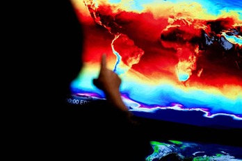 NASAko zientzialari bat satelite bidez iristen diren irudiak seinalatzen, gure planeta nola aldatzen ari den erakusteko.