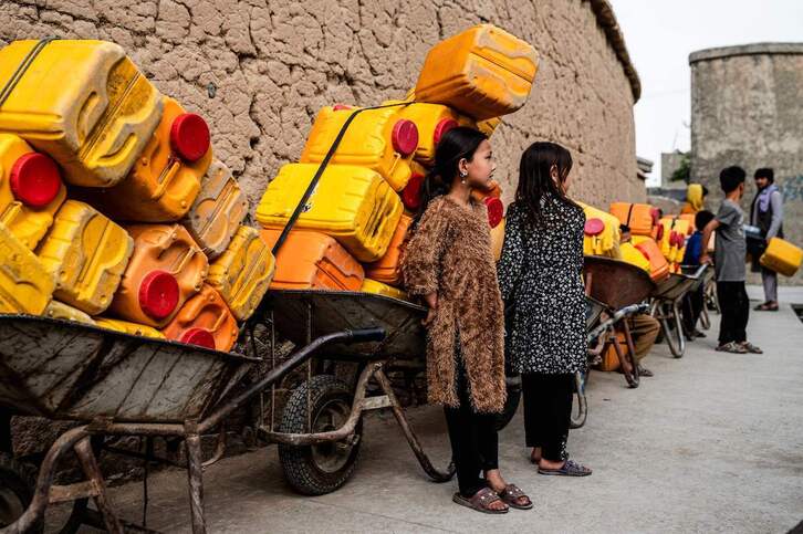 Niñas afganas hacen cola para conseguir agua potable.