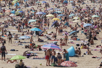 Donostiarras y turistas se refugian de las temperaturas en la Playa de la Concha.