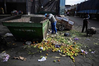 Un hombre busca en un contenedor de frutas fuera del Mercado Central de Buenas Aires.