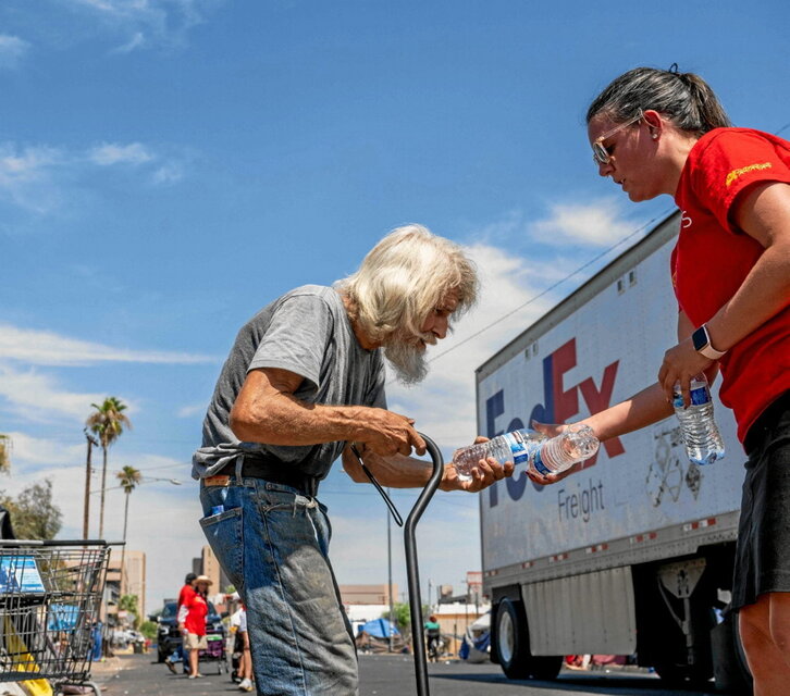 Una voluntaria entrega botellas de agua a un hombre sin hogar en Phoenix, Arizona.