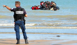 Un agente hace un gesto mientras la Policía francesa intenta evitar la salida de una balsa desde Sangatte hacia Gran Bretaña.