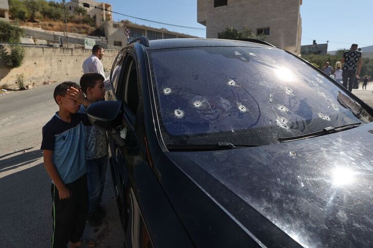 Unos niños miran dentro del coche en el que viajaba Fwazi Hani Majalfeh, que muestra el impacto de las balas israelíes. 