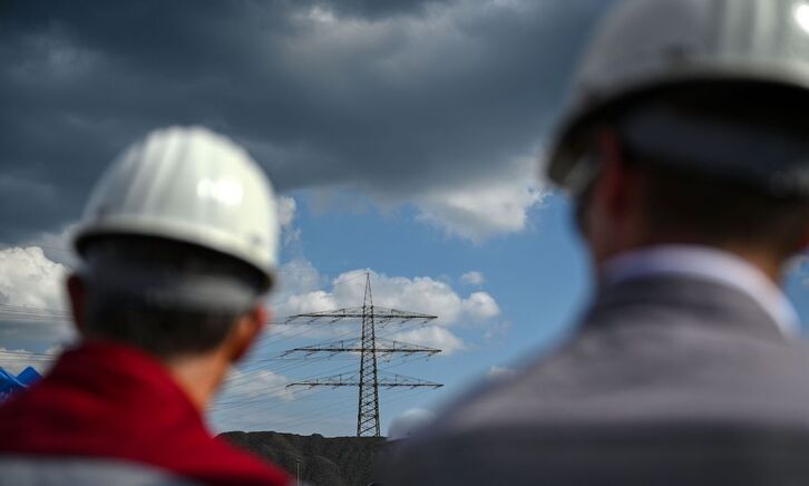 Dos empleados frente una torre eléctrica en una factoría de Duisburgo, Alemania.